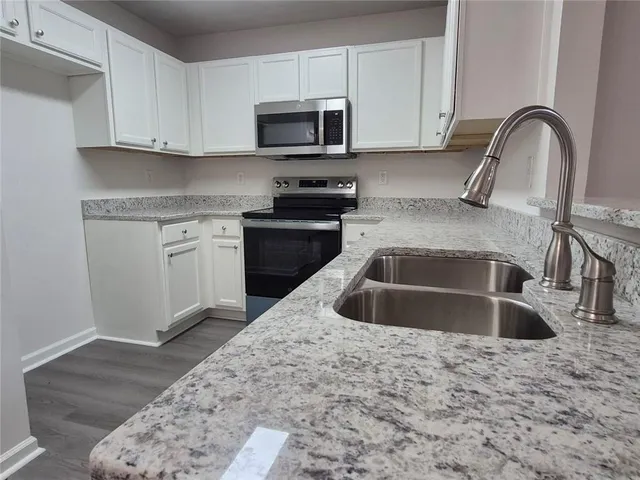 a kitchen with granite countertop a sink and a stove top oven