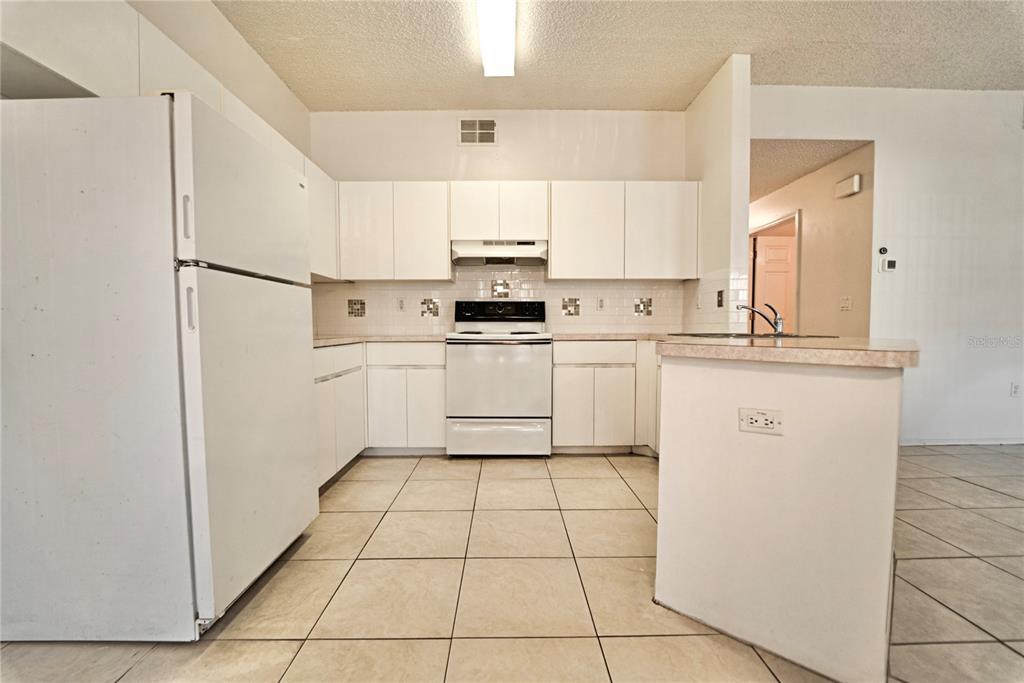 4150 Portillo Road, Unit 5 Spring Hill, FL 34608 - Photo 12 of 25 a kitchen with white cabinets a sink and white appliances