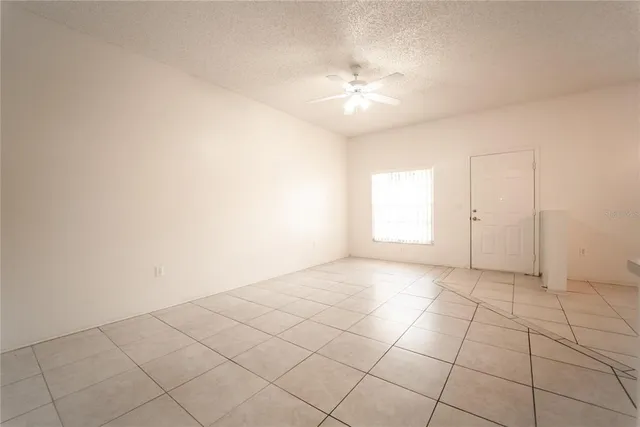an empty room with white walls and chandelier fan