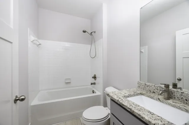 a bathroom with a granite countertop toilet sink and bathtub