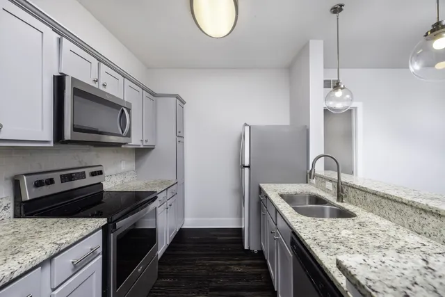 a kitchen with stainless steel appliances granite countertop a sink a microwave a stove and refrigerator