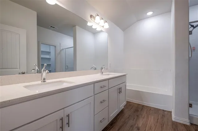 a spacious bathroom with a double vanity sink a mirror and a bathtub