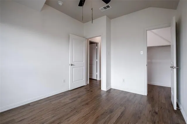 an empty room with wooden floor and a ceiling fan