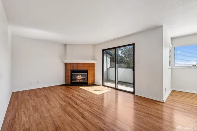 an empty room with wooden floor fireplace and windows
