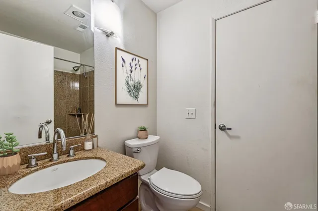 a bathroom with a granite countertop sink toilet a mirror and a shower