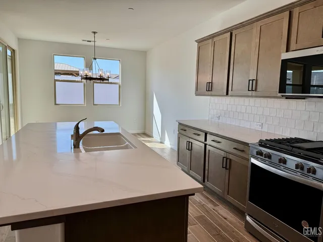 a kitchen with stainless steel appliances granite countertop a stove a sink dishwasher and a microwave oven with white cabinets