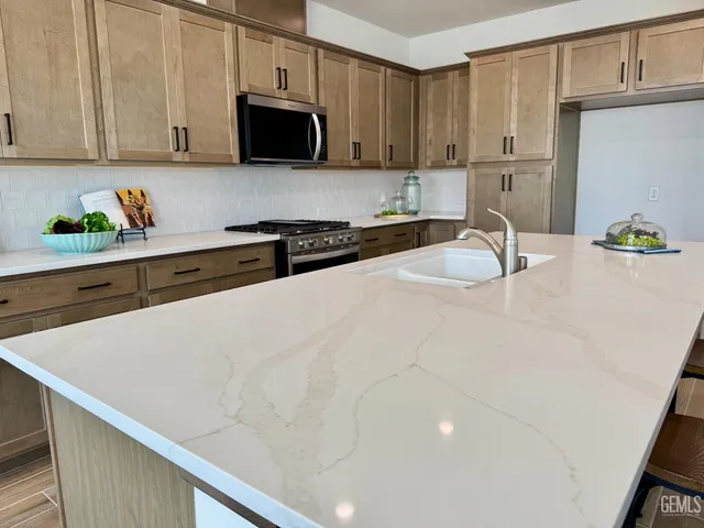 a kitchen with stainless steel appliances a sink a stove and a refrigerator with wooden cabinets