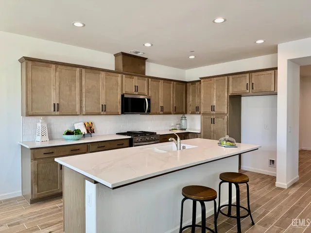 a kitchen with a refrigerator a stove a sink cabinets and wooden floor