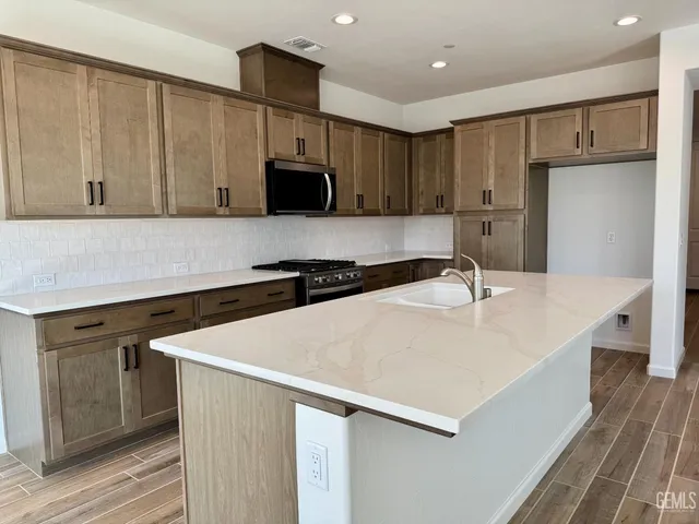 a kitchen with stainless steel appliances a sink a stove a refrigerator and cabinets