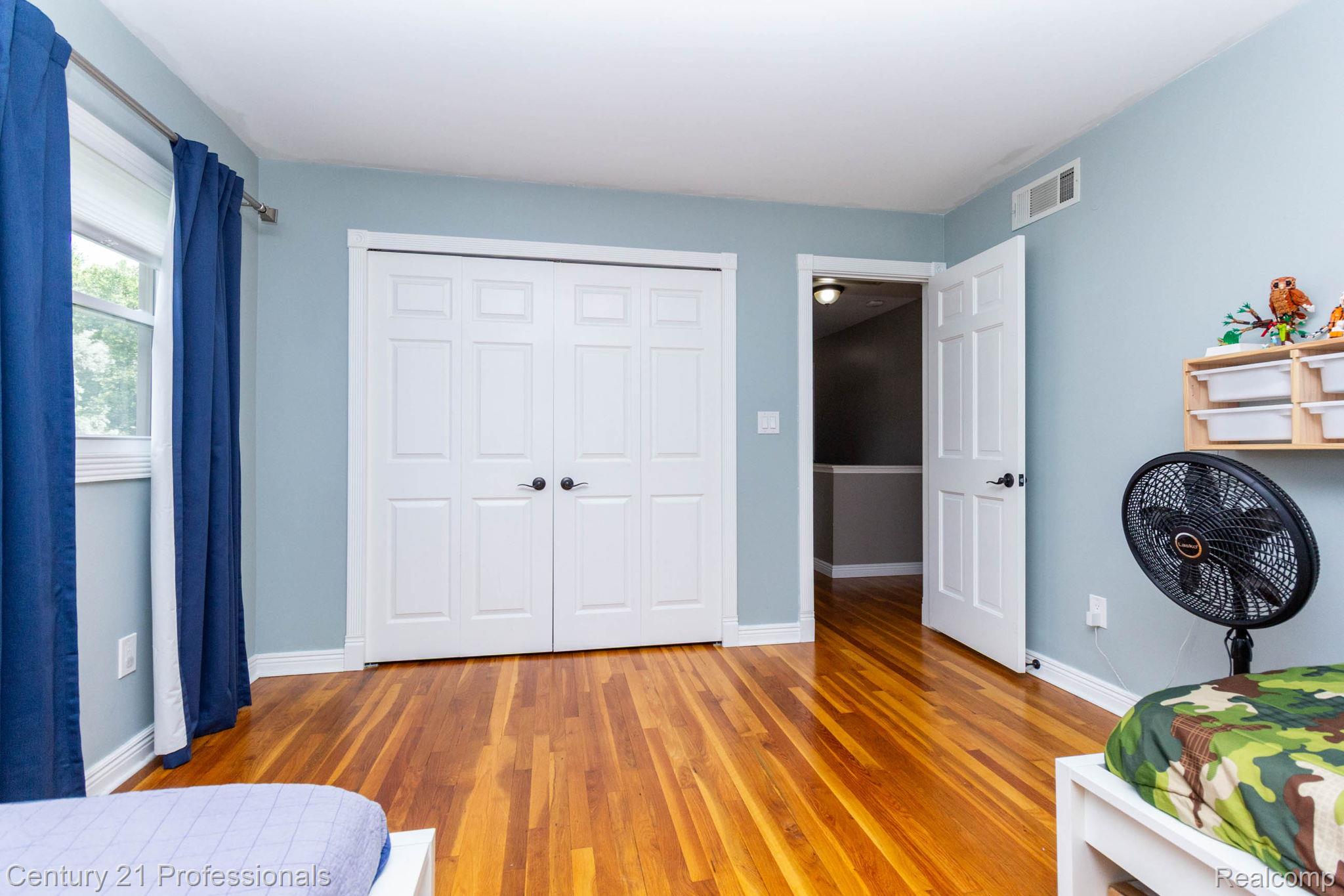 671 Bridgestone Drive Rochester, MI 48309 - Photo 28 of 50 Hardwood flooring throughout this room featuring a window with white trim, a double-door closet with black hardware, and a white six-panel interior door