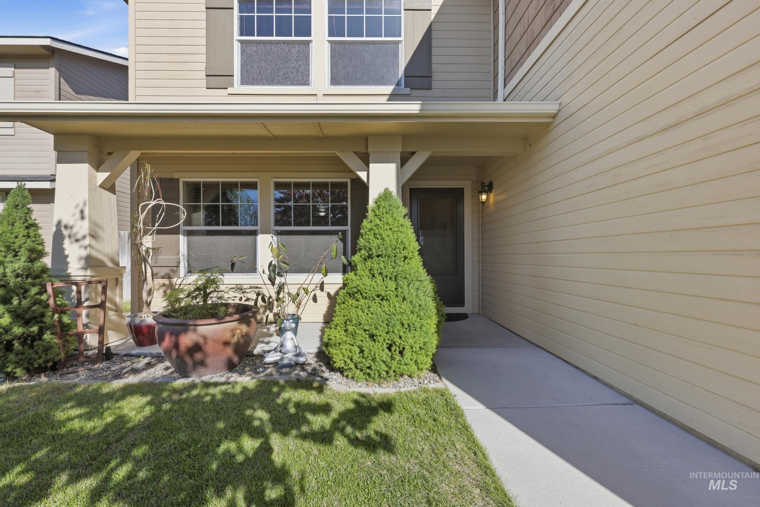 4855 South Chex Way Boise, ID 83709 - Photo 45 of 47 Entryway with covered porch, concrete walkway, and manicured landscaping featuring evergreen shrubs