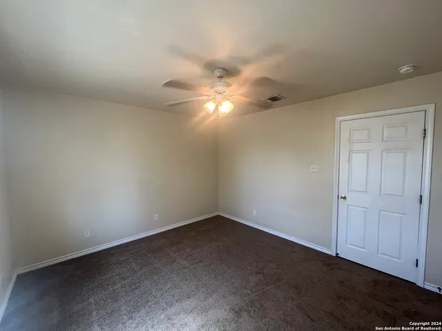 an empty room with windows and chandelier fan