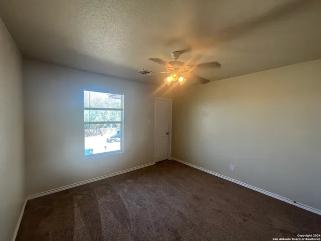 an empty room with windows and fan