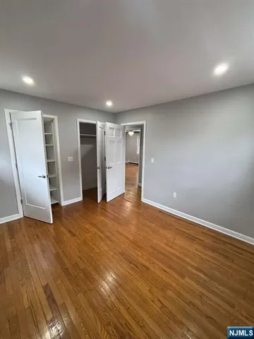 a view of an empty room with wooden floor and closet