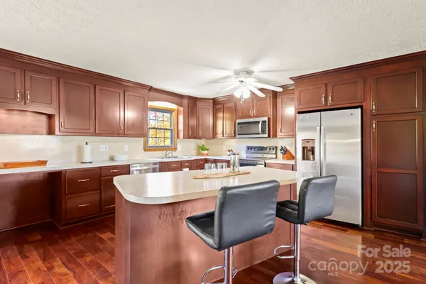 a kitchen with stainless steel appliances granite countertop a sink a stove a refrigerator cabinets and chairs