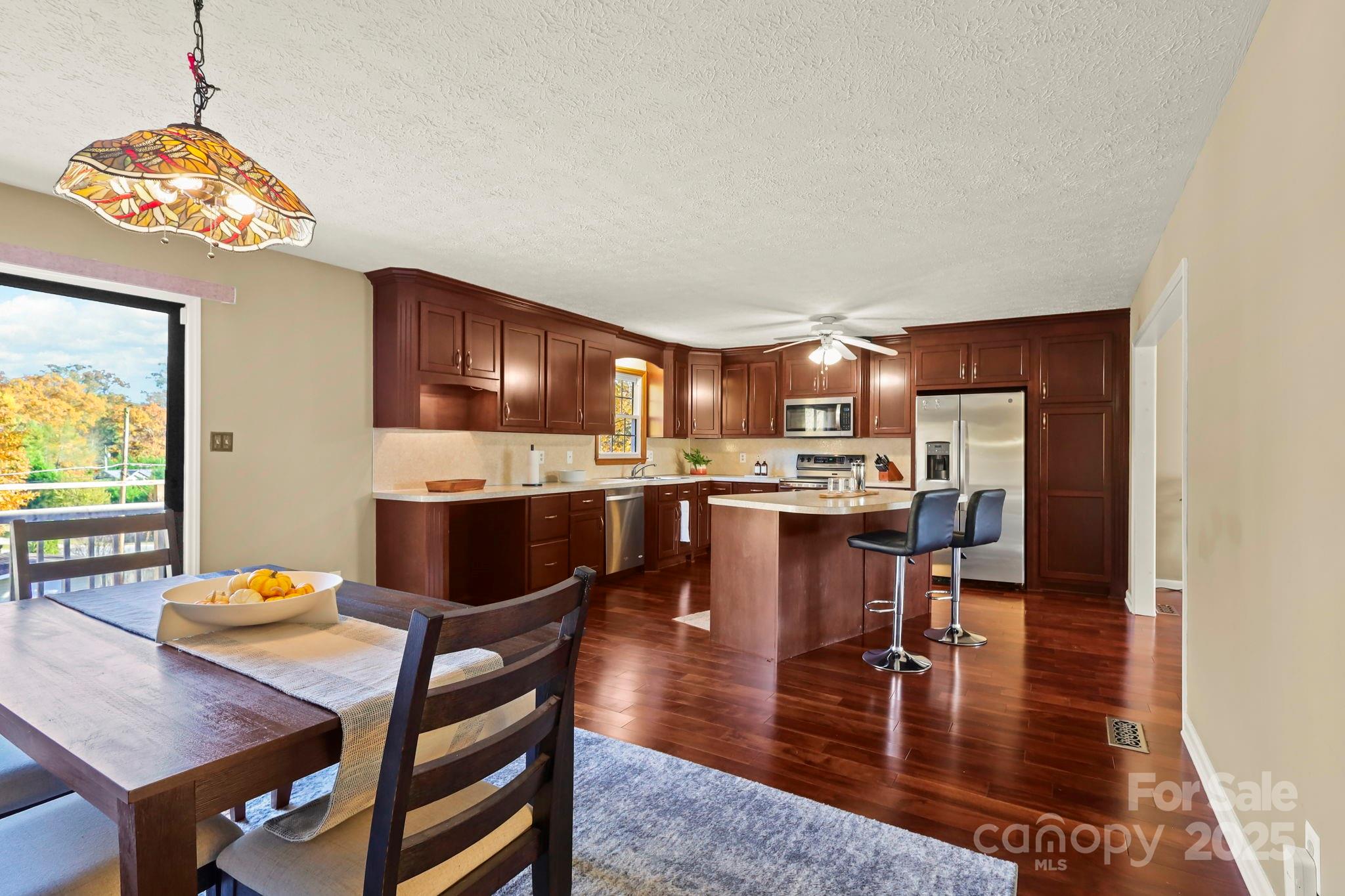2216 Olde Well Road Hudson, NC 28638 - Photo 14 of 48 a open dining room with stainless steel appliances kitchen island granite countertop a dining table chairs and a refrigerator