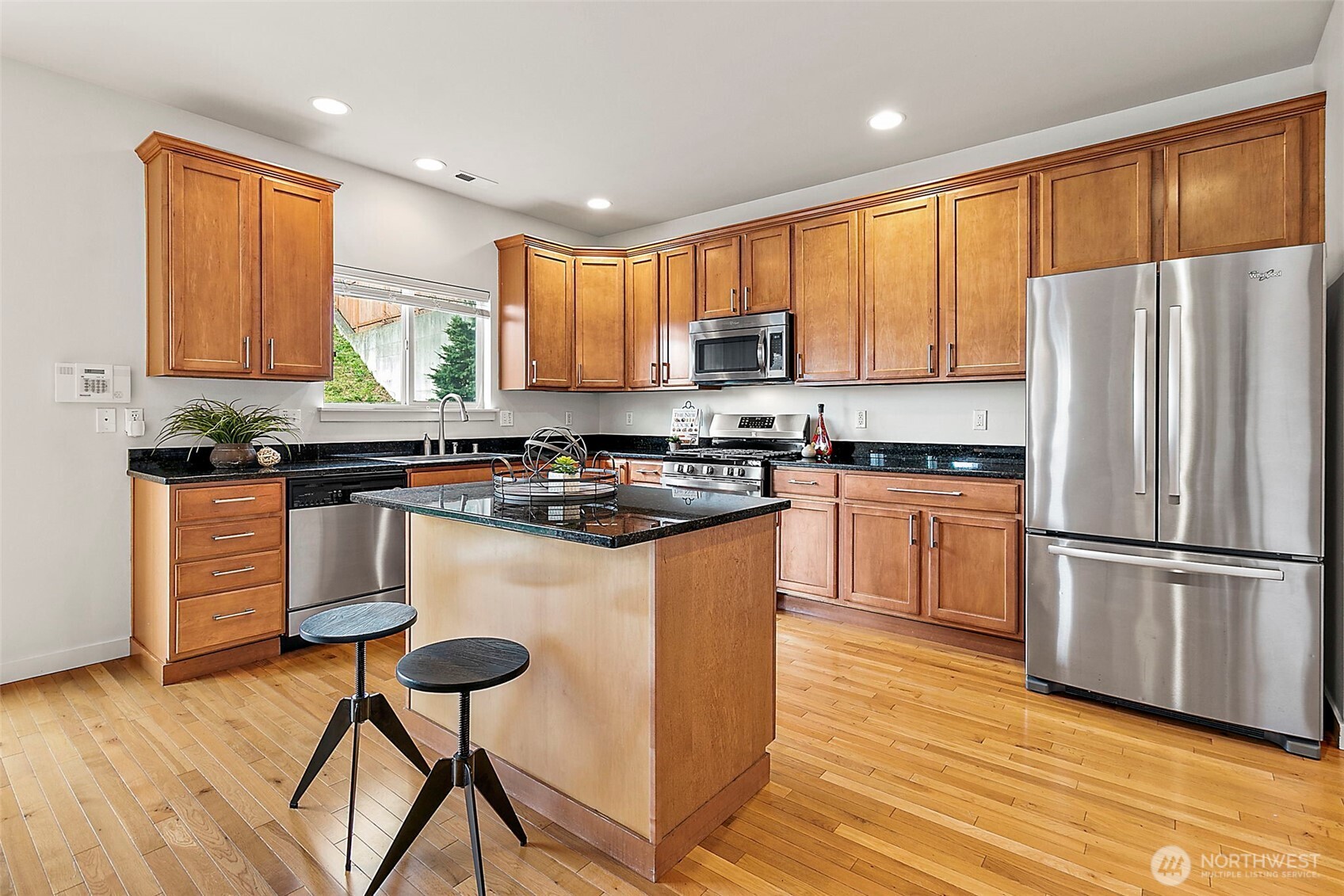 27729 257th Avenue Southeast Maple Valley, WA 98038 - Photo 9 of 40 a kitchen with kitchen island granite countertop wooden floors stainless steel appliances a sink and a window