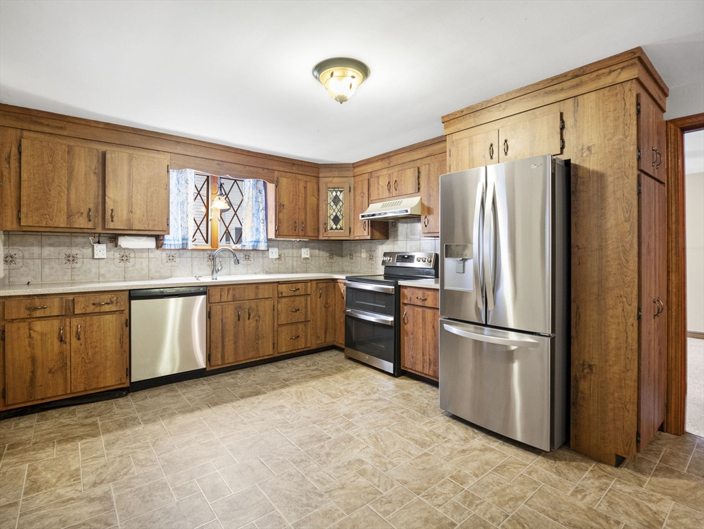 11 Dane Street Peabody, MA 01960 - Photo 12 of 27 a kitchen with stainless steel appliances granite countertop a refrigerator a sink dishwasher a stove with wooden cabinets and floor
