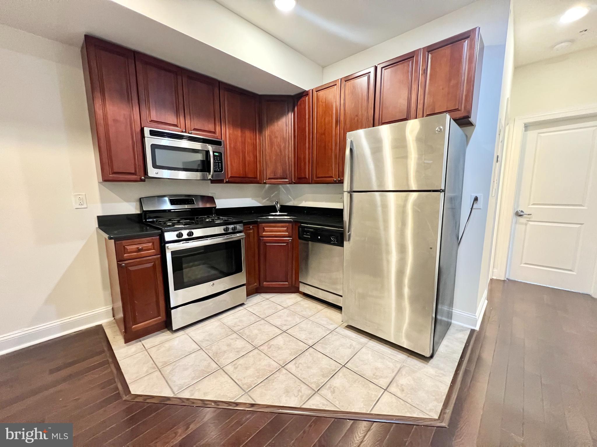 1806 North 16th Street, Unit A Philadelphia, PA 19121 - Photo 2 of 8 a kitchen with a refrigerator a stove top oven a refrigerator and cabinets