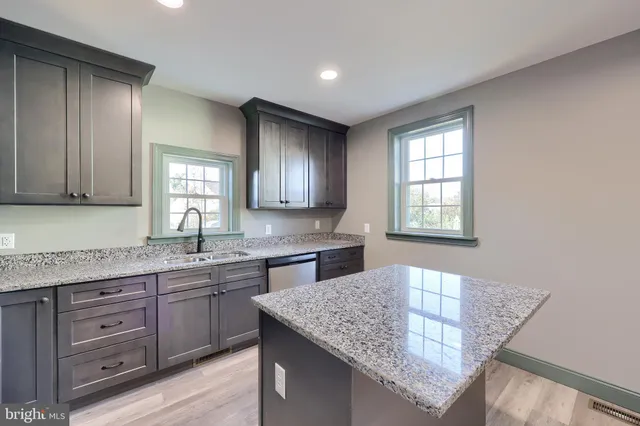 a kitchen with kitchen island granite countertop a sink window and cabinets