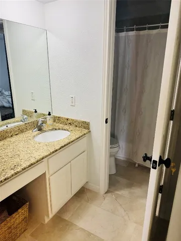 a bathroom with a granite countertop sink toilet and shower