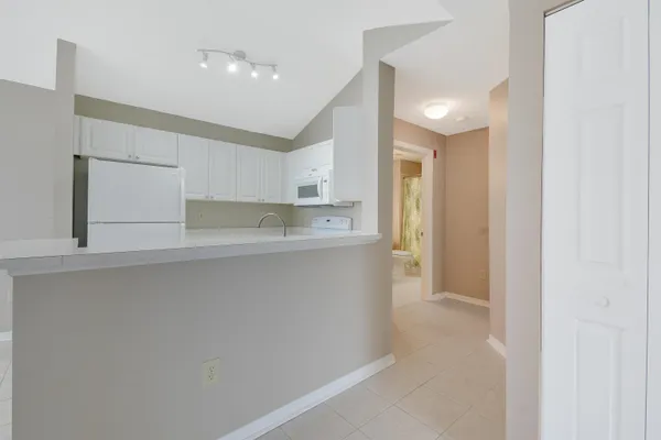 a kitchen with white cabinets and refrigerator