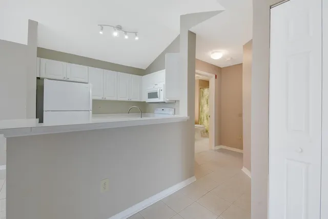 a kitchen with white cabinets and refrigerator