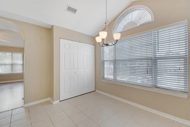 an empty room with wooden floor chandelier fan and windows