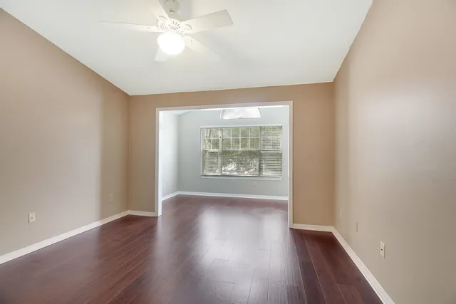 an empty room with wooden floor and windows