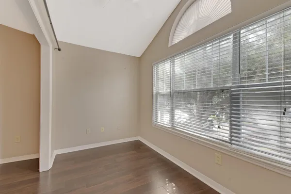 a view of empty room with wooden floor and fan