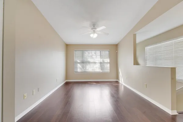 an empty room with wooden floor and windows