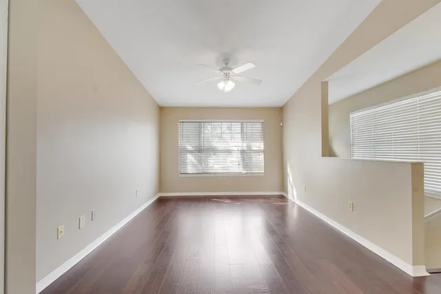 an empty room with wooden floor and windows