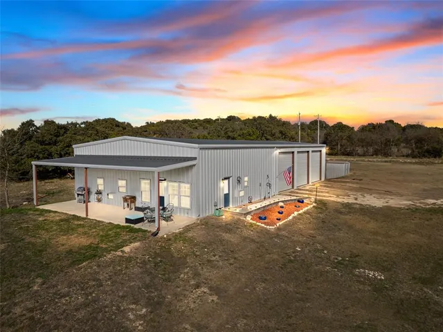 a view of a white house with a big yard and large trees