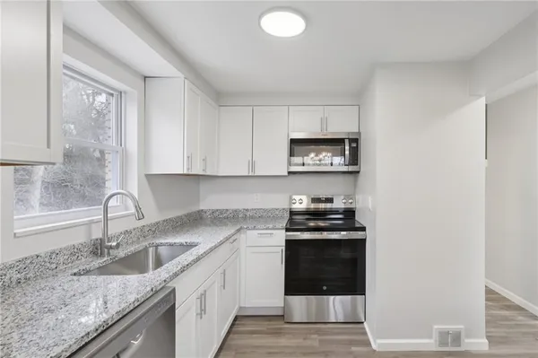 a kitchen with granite countertop a sink stove and cabinets