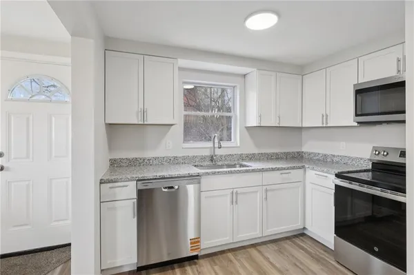a kitchen with granite countertop white cabinets and stainless steel appliances