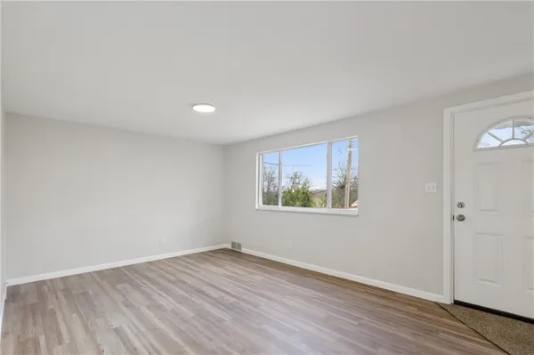 an empty room with wooden floor and window
