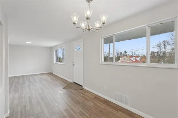 a view of an empty room with a window and wooden floor