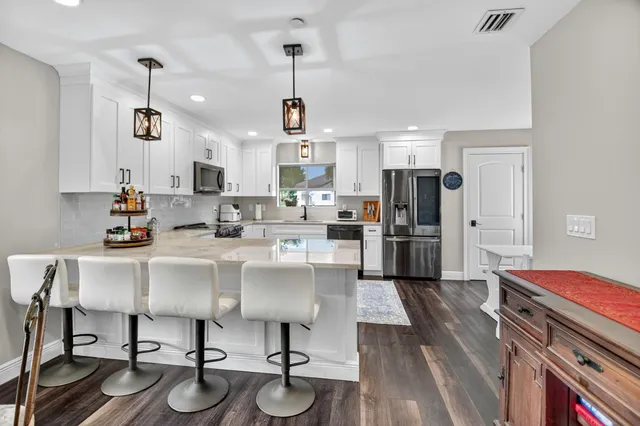 a kitchen with sink a refrigerator and chairs