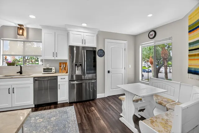 a kitchen with a refrigerator a stove a sink and a dining table with wooden floor