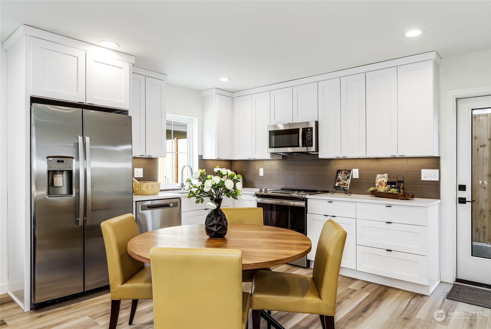 9033 15th Avenue Southwest Seattle, WA 98106 - Photo 4 of 17 a kitchen with a refrigerator a stove a kitchen island and chairs in it