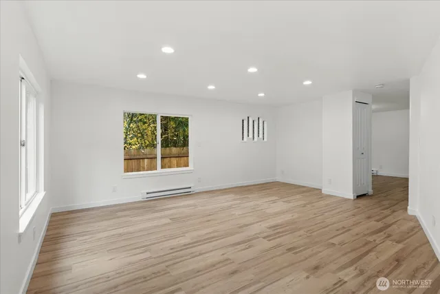 a view of an empty room with wooden floor and a window