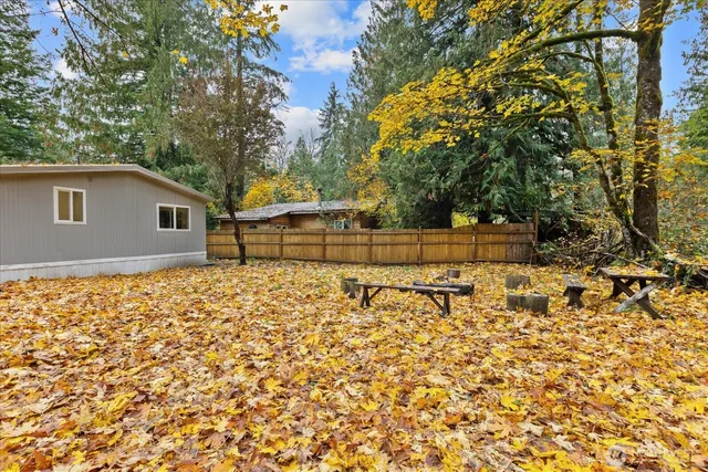 a backyard of a house with large trees and covered with wooden fence