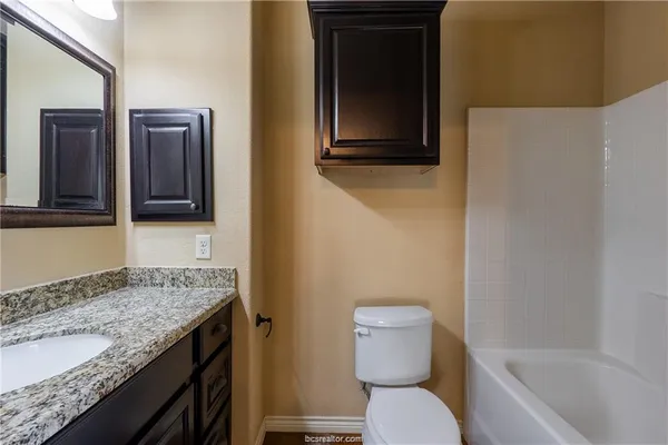 a bathroom with a granite countertop toilet sink and mirror
