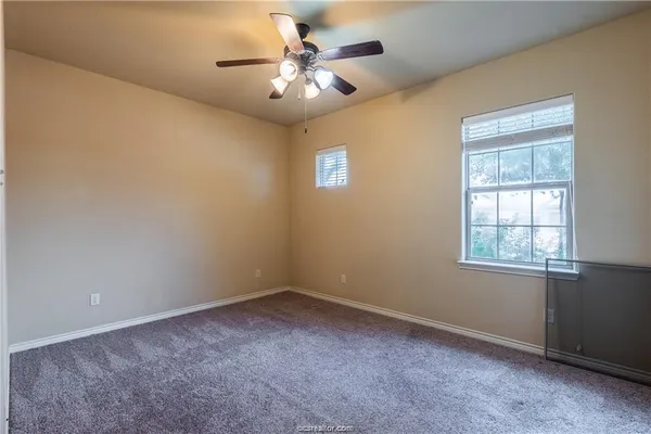 an empty room with a chandelier fan and windows