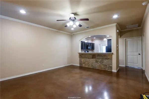 an empty room with kitchen and chandelier fan
