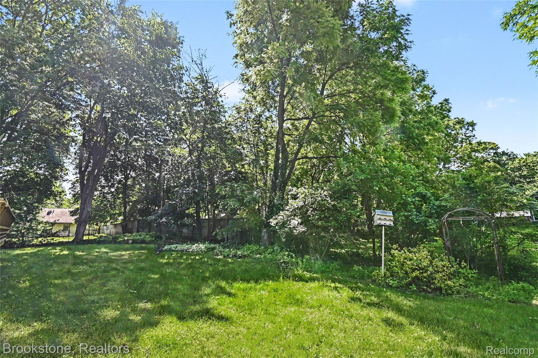 416 East Maple Street Mason, MI 48854 - Photo 18 of 18 Expansive green lawn surrounded by mature trees, creating a private outdoor environment