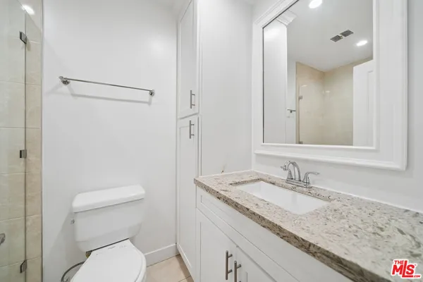 a bathroom with a granite countertop sink toilet and shower