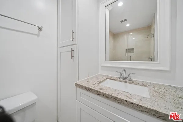 a bathroom with a granite countertop sink toilet and shower