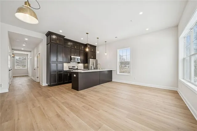 a large white kitchen with kitchen island a sink wooden floor and a refrigerator