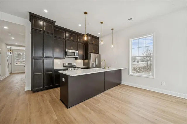 a kitchen with kitchen island granite countertop a sink cabinets and stainless steel appliances
